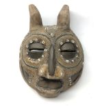 African carved softwood mask with eyes, nose and mouth apertures, inlaid cowrie shells,