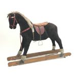 Early 20th century plush covered rocking horse, saddle and stirrups, no trestle base,