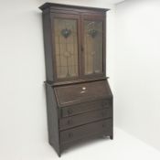 Early 20th century oak bureau bookcase with stained lead glazed doors above fall front,