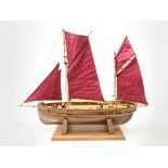 A wooden model of a twin masted fishing yawl, on stand, L60cm.