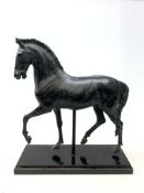 A large bronze style model of a horse, raised upon a black rectangular base, H59cm.