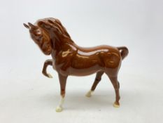 A Beswick figurine, modelled as a chestnut horse with front leg raised, with printed mark beneath,