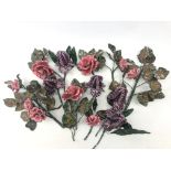A small collection of ceramic flowers, in the form of pink roses and purple buds,