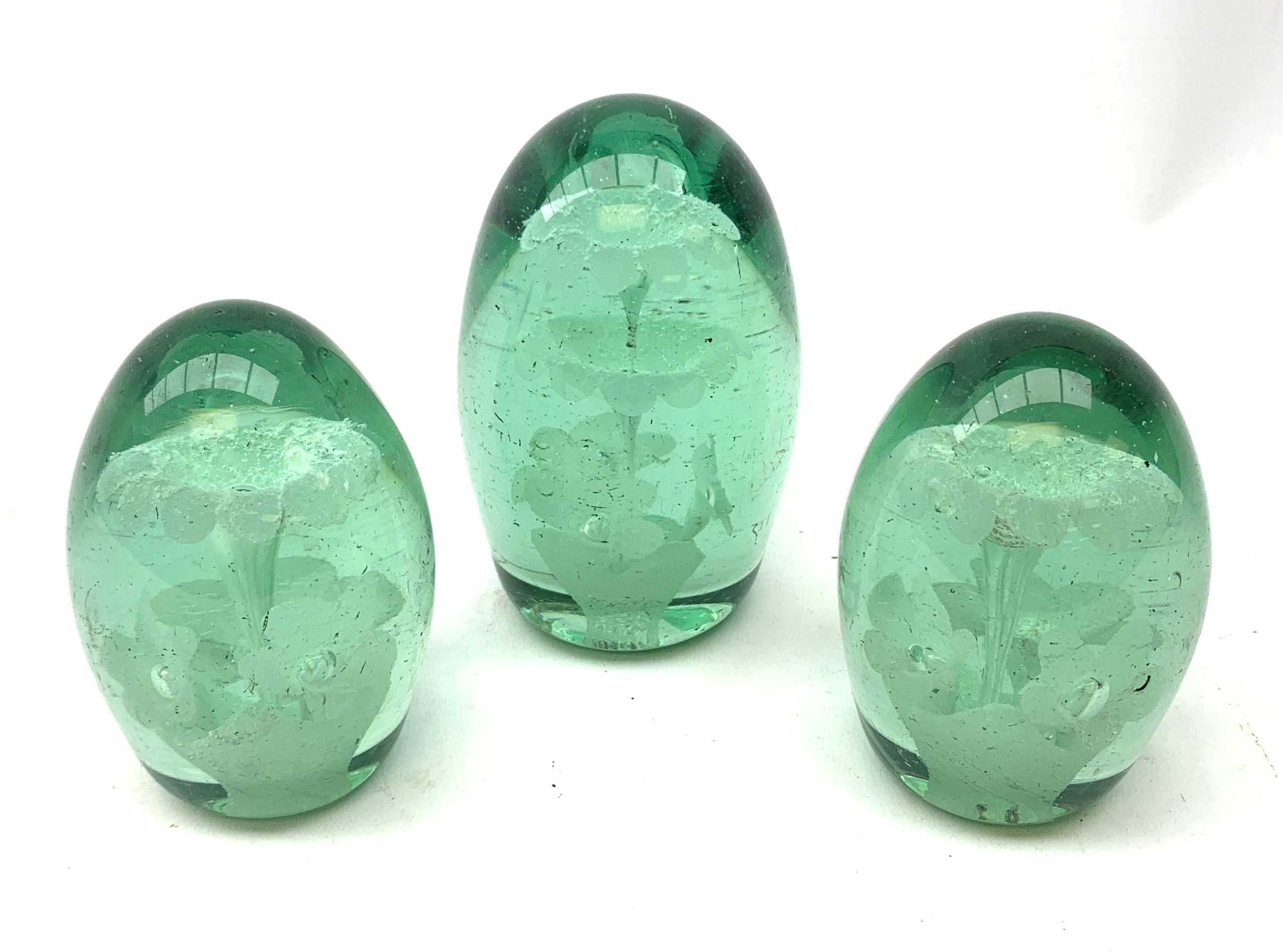 A pair of Victorian green glass dump paperweights, together with another larger Victorian example,