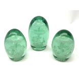 A pair of Victorian green glass dump paperweights, together with another larger Victorian example,