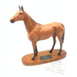 A Bewick figurine, modelled as a chestnut horse, Red Rum, raised upon an oval wooden base with plaqu