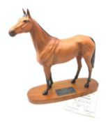 A Bewick figurine, modelled as a chestnut horse, Red Rum, raised upon an oval wooden base with plaqu