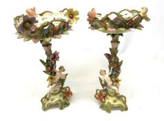 A pair of Continental porcelain centre pieces, the footed bases leading to a stems modelled with flo