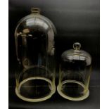 Two Victorian glass cloches, the largest H44cm (a/f), smaller H28cm.