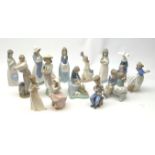 A group of thirteen Nao figurines, together with one Lladro figurine, each with printed mark beneath