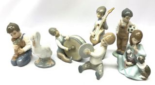 A group of Lladro and Nao figurines, comprising a trio modelled as boys playing instruments, boy wi