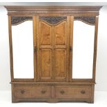 Early 20th century carved oak triple wardrobe, with two shaped mirrored doors, two drawers to base w