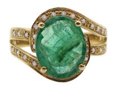 Gold oval emerald ring with diamond swirl surround and shank, stamped 14K