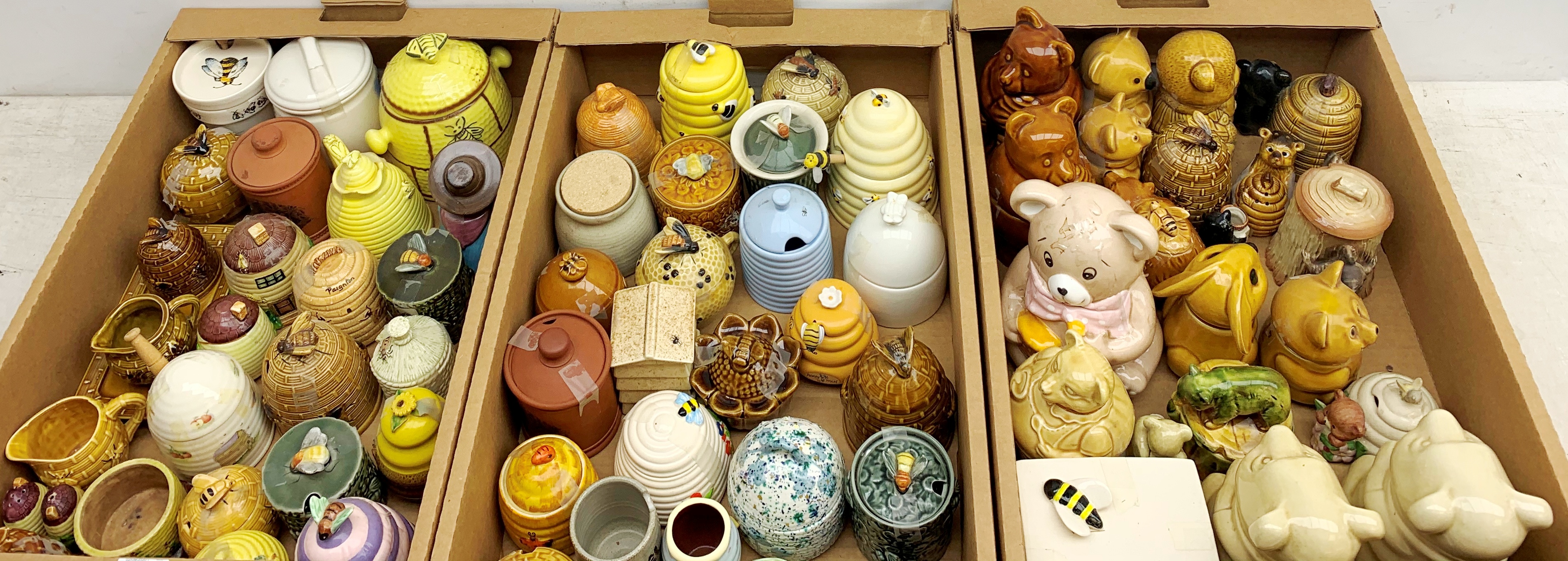 A large collection of various ceramic honey pots, to include examples in the form of bee skeps, etc.