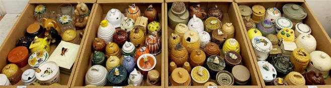 A large collection of various ceramic honey pots, to include examples in the form of bee skeps, etc