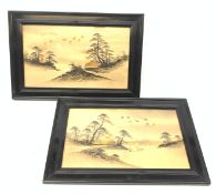 A pair of Japanese artworks, each depicting a landscape and heightened with gilt, in glazed ebonised