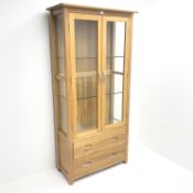 Light oak display cabinet, projecting cornice, two doors enclosing glazed shelves above two drawers