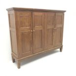 Traditional pine floor standing cupboard fitted with four panelled doors enclosing shelves, square t