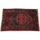 Afghan hand knotted red ground rug, diamond centre with geometric pattern, 195cm x 122cm