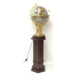 An electric operating rotating gem stone style globe with brass mount and wooden base, upon wooden h