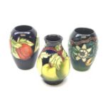 Three Moorcroft vases, the first of bulbous form tube line decorated with green apples against a dar