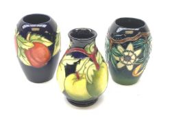 Three Moorcroft vases, the first of bulbous form tube line decorated with green apples against a dar