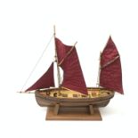 A wooden model of a twin masted fishing yawl, on stand, L60cm.