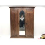 Irish Arts & Crafts walnut triple wardrobe circa 1908, projecting cornice above three doors enclosin