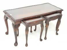 Late 20th century figured mahogany nest of tables, shaped moulded top with inset glass, on cabriole