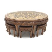Eastern glass topped oval table decorated in high relief with six integral stools, W124cm, H50cm, D8