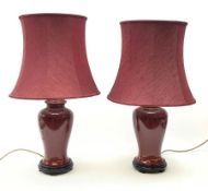 A pair of burgundy ceramic lamps, of baluster form, with matching burgundy shades, overall H71cm.