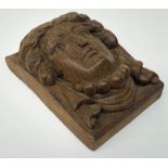 An oak furniture or architectural detail of oblong form carved in high relief with the head of a lad