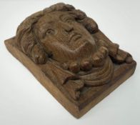 An oak furniture or architectural detail of oblong form carved in high relief with the head of a lad