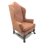 Georgian style mahogany framed high wing back armchair, upholstered in a patterned terracotta studde