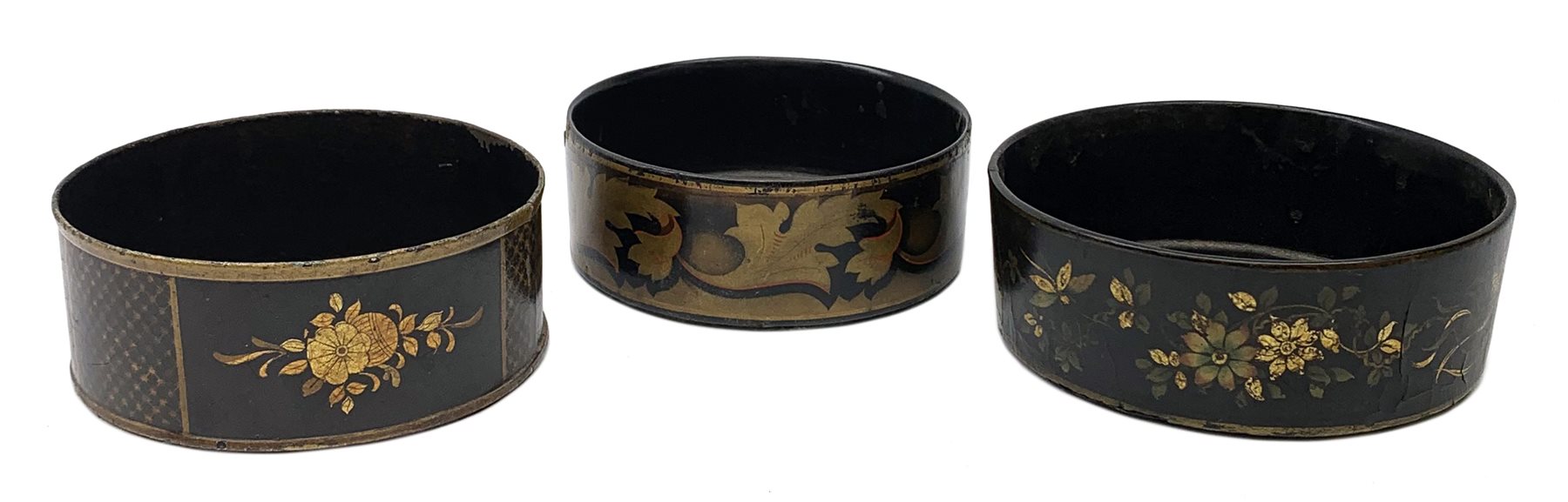 Two Regency black papier-maché wine coasters, together with a toleware example, each with gilt folia