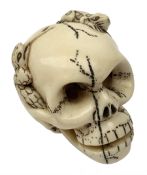 Japanese Meiji carved ivory netsuke, modelled as a skull, the top carved with two toads, and script