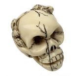 Japanese Meiji carved ivory netsuke, modelled as a skull, the top carved with two toads, and script