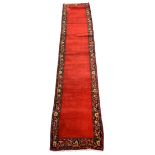 Persian Tabriz runner rug, plain red ground field, trailing stylised foliage and flower head border,