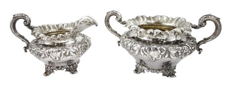 William IV silver twin handled sugar bowl and milk jug, embossed foliate decoration on four scroll f