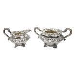 William IV silver twin handled sugar bowl and milk jug, embossed foliate decoration on four scroll f