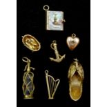 Seven 9ct gold charms including a soda siphon, baby in a basket, harp, Indian shoe and a book, hallm