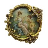 19th century painting on ivory depicting Cupid and maiden, in ornate gilt brooch set with split pear