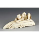 An ivory okimono of a boy planing the bottom of and upturned boat 3" x 1 1/2"