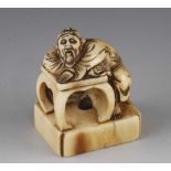 An ivory netsuke of a sage sleeping on a table