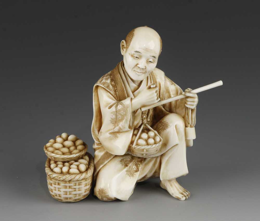 A 4" ivory okimono of a man weighing eggs signed