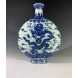 A Chinese blue and white porcelain moon flask, painted in underglaze blue with dragons amongst cloud