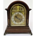 A late 19th century German mahogany bracket clock with arched top, the brass mask with cast