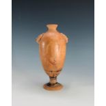 A terracotta footed vase, probably Roman, with applied masks and remnants of figural decoration.