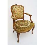 A French walnut upholstered open armchair, 19th century, with foliate carved cabriole legs.Condition