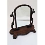 A Victorian mahogany dressing table mirror, with an arched mirrored plate on a serpentine shaped
